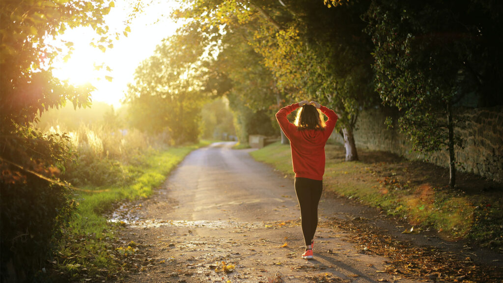 Person walking outside in the morning sun feeling free of stress knowing they had Aetna mental health benefits.
