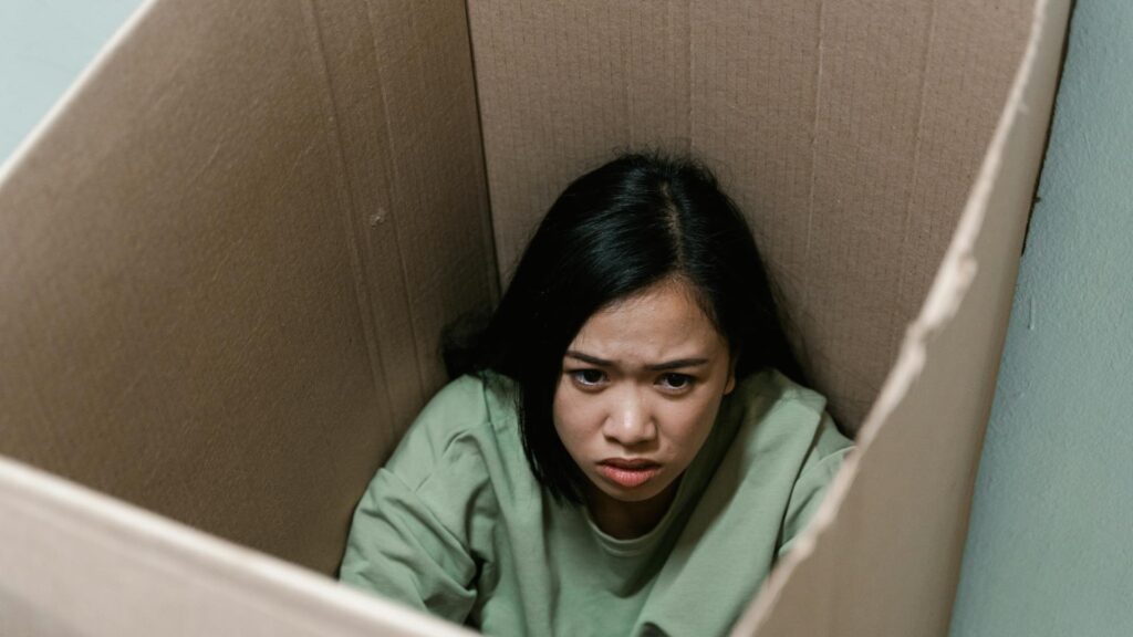 Distressed woman sitting in a box.