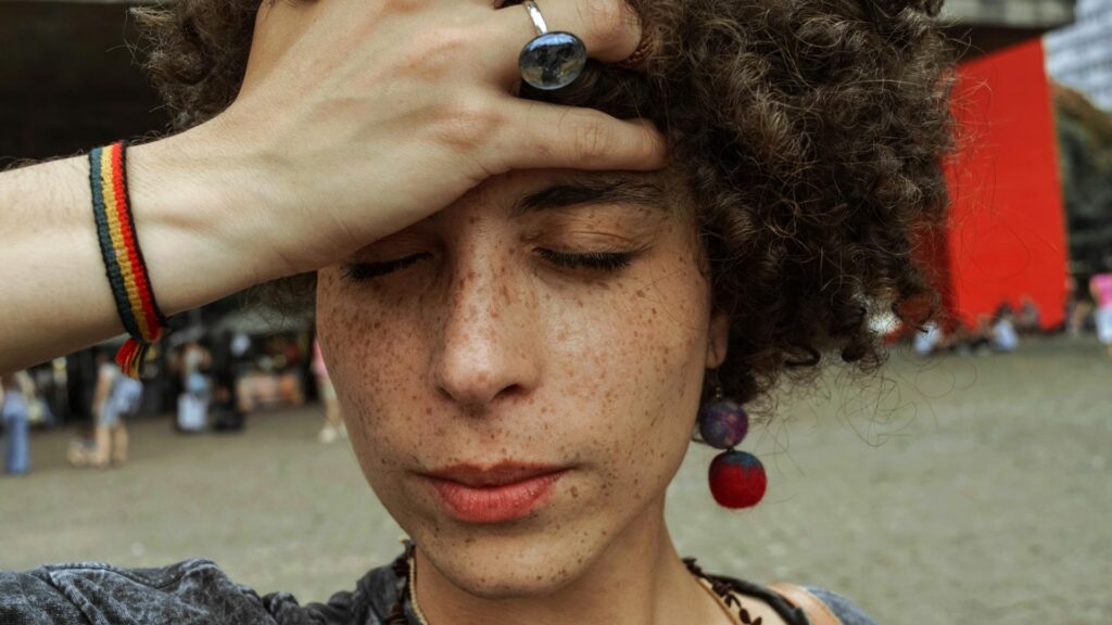 Woman grasps forehead.