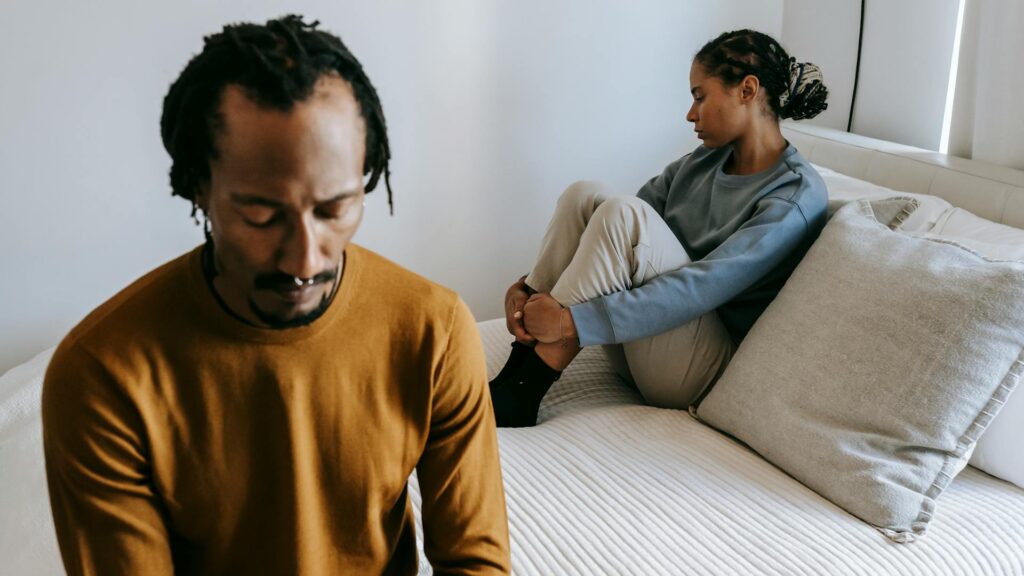 Distraught couple on bed.