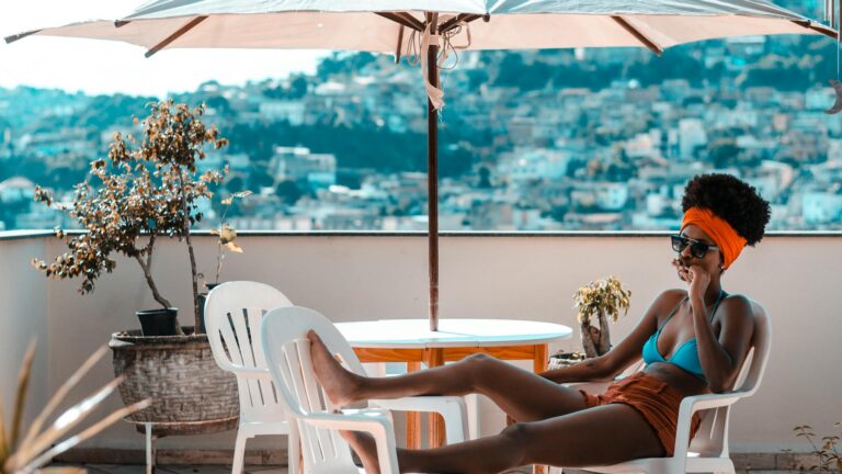 Woman reclines in a pool chair and enjoys her free time under an umbrella.